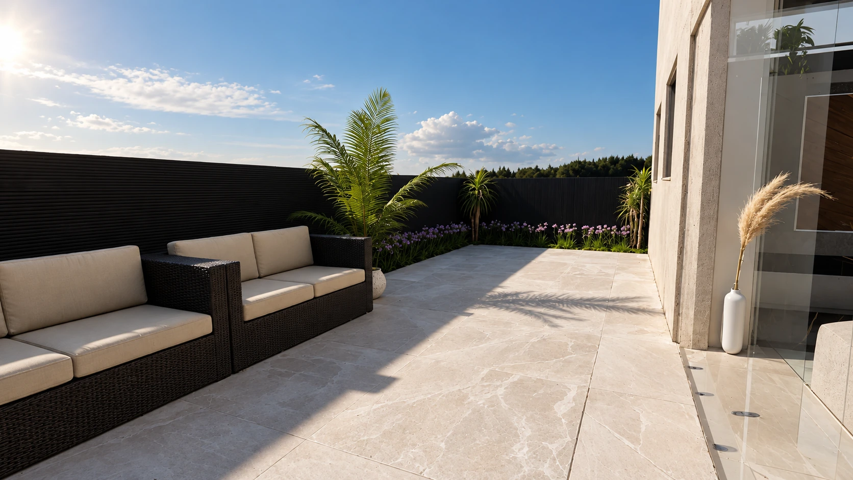 Terraço com sofás claros, palmeiras e portas de vidro.